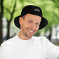Happy looking man wearing black hat with text 100% genuine human in nature
