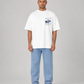 Man wearing a white t-shirt with a graphic design and light blue jeans on a gray background