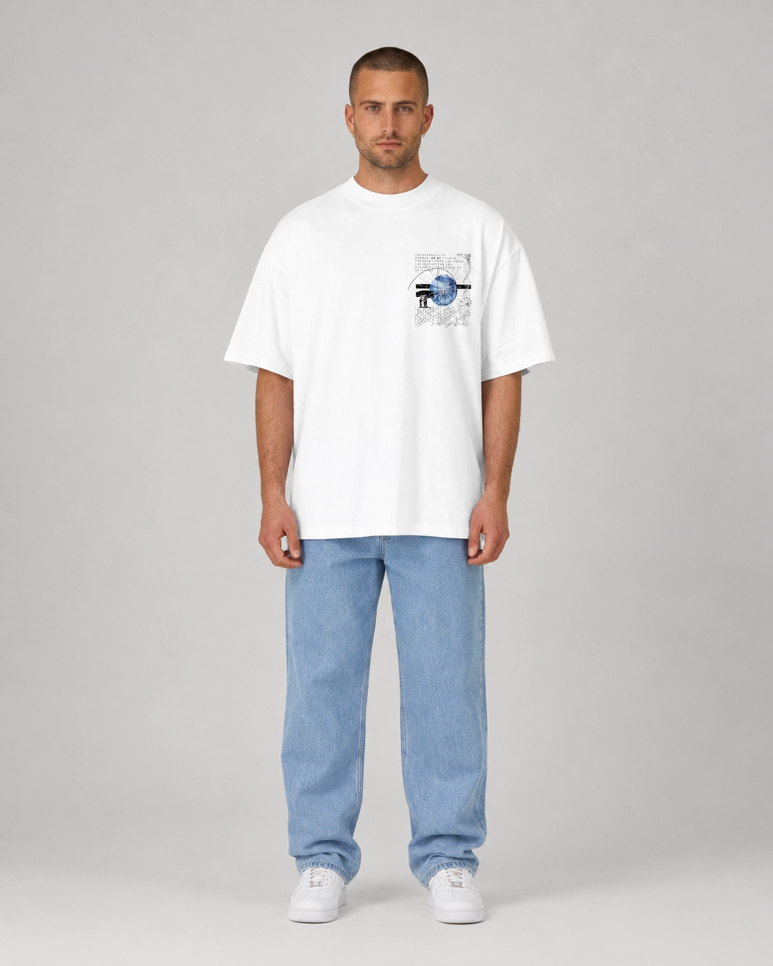 Man wearing a white t-shirt with a graphic design and light blue jeans on a gray background