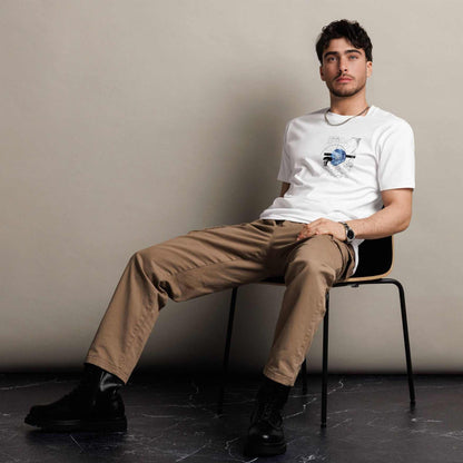 Man sitting on a chair wearing a white Christian t-shirt and beige pants against a plain background