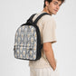A man wearing a beige t-shirt and light beige pants is shown from the back and side, carrying a black backpack with a white, black, and gold palm leaf pattern against a light gray studio background.