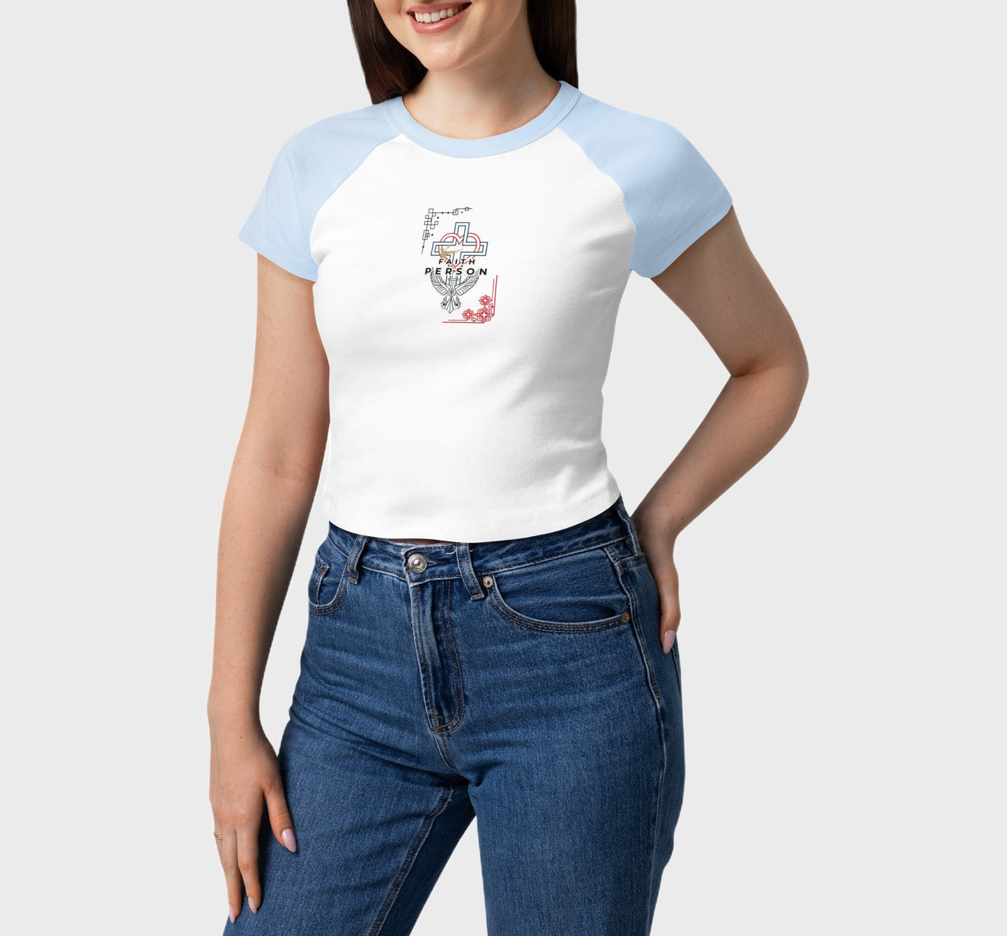 Person wearing a white and blue baseball shirt with a graphic design, paired with blue jeans on a plain background