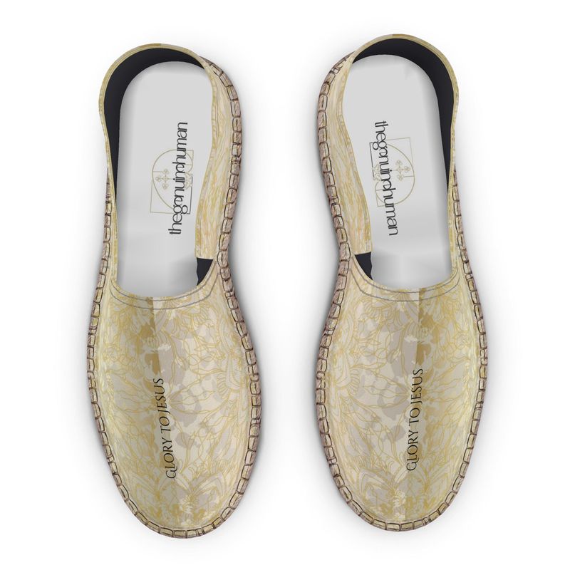 Pair of beige espadrilles with floral pattern on a white background