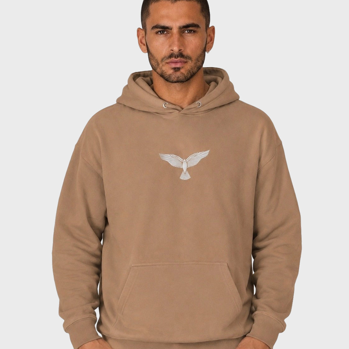 Man wearing a brown hoodie with an eagle logo on a white background