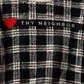 A close-up of a black and off-white plaid turtleneck sweater featuring a red heart and the text 'THY NEIGHBOR' across the chest.