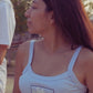 Woman wearing a white tank top with text outdoors