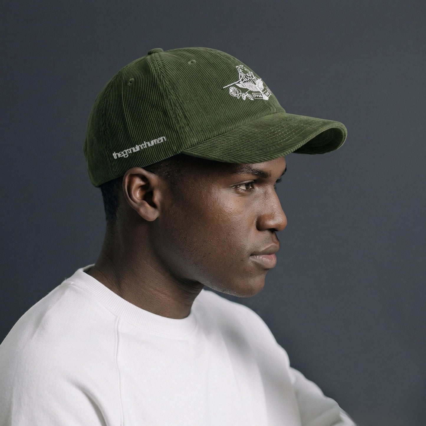 Person wearing a green cap with a logo on a dark background