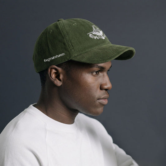Person wearing a green cap with a logo on a dark background