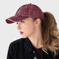 Woman wearing a maroon cap with text and a cross on a plain background