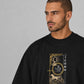 Man wearing a black t-shirt with a gold graphic design on a gray background