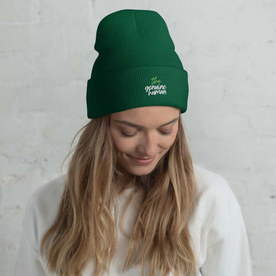 Woman wearing pine green beanie hat with text thegenuinehuman